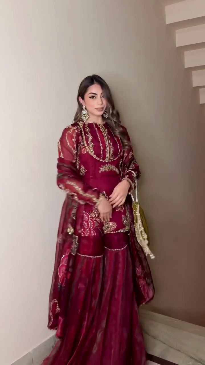 This breathtaking ensemble features a deep maroon kurti beautifully embellished with intricate golden embroidery ✨🌺. The embroidery includes floral motifs, structured patterns, and shimmering threadwork that adds richness to the entire look. The kurti is designed with full sleeves made from lightweight sheer fabric, decorated with matching motifs that create a royal and festive charm 👑💫.Maroon Apparel Collection The sharara bottom flows gracefully with wide flares, enhancing every step with elegance and movement 💃💕. The layered design adds volume while still maintaining comfort, ensuring you look stylish without compromising ease. The sharara is adorned with embroidered borders and delicate lines that beautifully complement the kurti 🌟🌿.